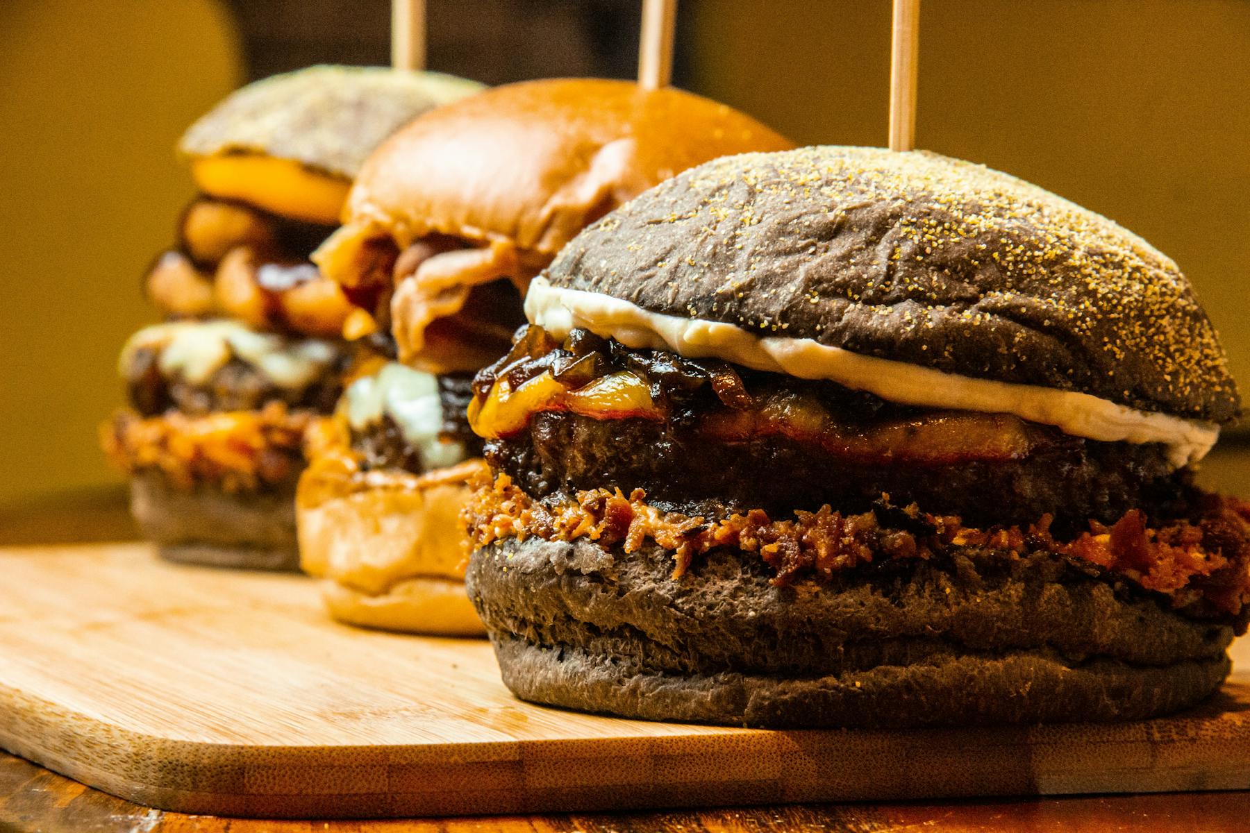 An array of gourmet burgers with diverse toppings, displayed on a platter.
